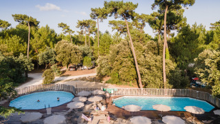 Piscina al aire libre en Huttopia Oléron les Pins, rodeada de árboles en Nouvelle-Aquitaine, Francia.