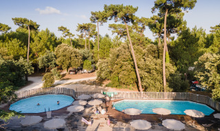 Piscina al aire libre en Huttopia Oléron les Pins, rodeada de árboles en Nouvelle-Aquitaine, Francia.