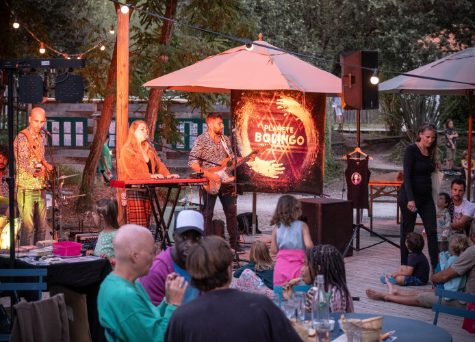 Live muziekoptreden bij Huttopia Oléron les Pins met gezinnen die genieten van een gezellige avond.