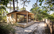 Chalet Evasion en Huttopia Arcachon, Francia, cabaña de madera en el bosque con terraza y sillas.
