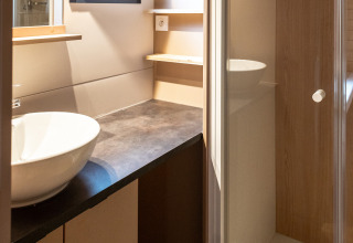 Bagno moderno nello Chalet Evasion a Huttopia Arcachon, Francia, con cabina doccia, lavabo a ciotola e finestra aperta.