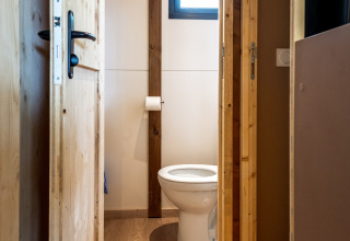 Billede af et simpelt badeværelse med trægulv og et toilet inde i Chalet Evasion ved Huttopia Arcachon.