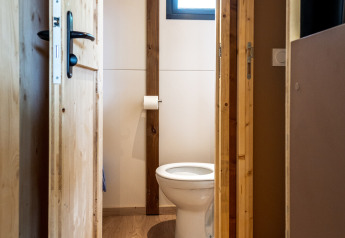 Foto di un semplice bagno con pavimento in legno e WC nello Chalet Evasion presso Huttopia Arcachon, Francia.