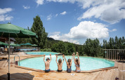 Bambini seduti a bordo piscina a Huttopia Font-Romeu, parco vacanze in Occitania, Francia, circondati dalla natura.