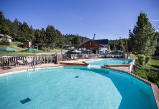 Buitenzwembad met ligzetels en parasols bij het Huttopia Font-Romeu vakantiepark in Occitanië, Frankrijk.