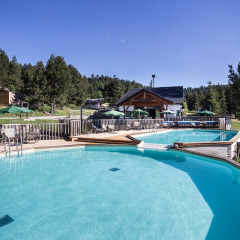 Piscina al aire libre con tumbonas y sombrillas en Huttopia Font-Romeu, parque vacacional en Occitania, Francia.