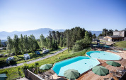 Outdoor pools with sun umbrellas and camper vans at Huttopia Font-Romeu holiday park in Occitanie, France