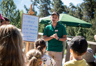 Monitor geeft uitleg over schattenjacht aan kinderen op vakantiepark Huttopia Font-Romeu in Occitanie, Frankrijk.