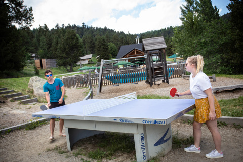 Dos personas juegan al tenis de mesa al aire libre en el parque vacacional Huttopia Font-Romeu en Occitania, Francia.