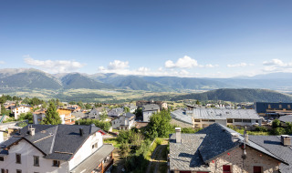 Vista de los tejados de Font-Romeu, Occitanie, Francia, con montañas verdes y cielo azul al fondo.