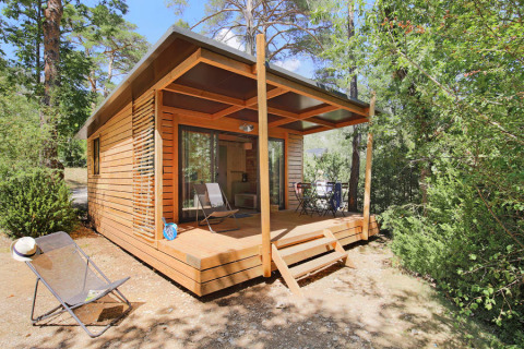 Chalet Victoria de madera, con terraza cubierta y sillas, rodeado de bosques y naturaleza tranquila.