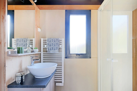 Moderne badeværelse på Chalet Victoria, Huttopia Arcachon, Frankrig, med vask, spejl og bruser.