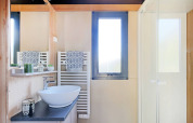Moderne badeværelse på Chalet Victoria, Huttopia Arcachon, Frankrig, med vask, spejl og bruser.