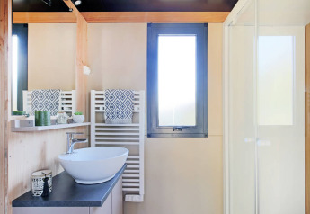 Moderne badeværelse på Chalet Victoria, Huttopia Arcachon, Frankrig, med vask, spejl og bruser.