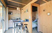 Cocina luminosa y moderna con barra y taburetes, vista al dormitorio en el Chalet Victoria, Huttopia Arcachon, Francia.