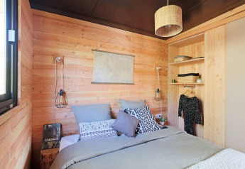 Holzverkleidetes Schlafzimmer im Chalet Victoria, Huttopia Arcachon, Frankreich, mit gemütlicher moderner Einrichtung.