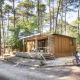 Træhytte ved navn Chalet Portland omgivet af høje træer, cykel parkeret foran, fredelig atmosfære.