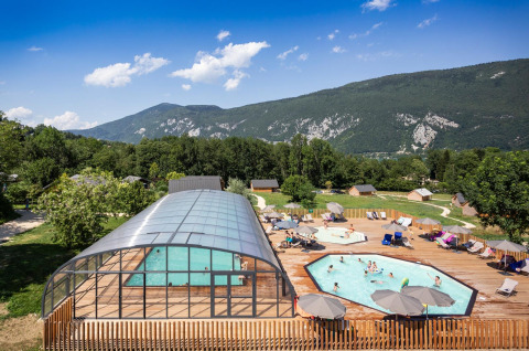 Parque vacacional Huttopia Lac d’Aiguebelette en Auvergne-Rhône-Alpes con piscina, terraza y vistas a las montañas.