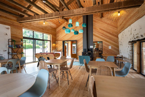 Vista interior de un espacio común acogedor en Huttopia Lac d’Aiguebelette con decoración de madera y sillas azules.
