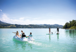 People enjoying pedal boating and paddleboarding at Huttopia Lac d’Aiguebelette, Auvergne-Rhône-Alpes, France.