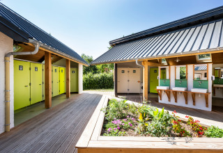 Moderne buitenbadkamers met groene deuren en wastafels bij Huttopia Lac d’Aiguebelette, Frankrijk.