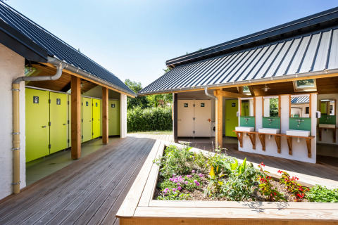 Modernas instalaciones de baño al aire libre con puertas verdes en Huttopia Lac d’Aiguebelette, Francia.