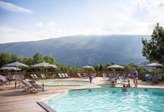 Outdoor swimming pool with deck chairs and umbrellas at Huttopia Lac d’Aiguebelette, Auvergne-Rhône-Alpes, France.