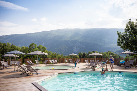 Piscine extérieure avec chaises longues et parasols à Huttopia Lac d’Aiguebelette, Auvergne-Rhône-Alpes, France.