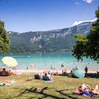 Personas se relajan junto al lago cerca de Saint Alban de Montbel, rodeados de montañas en Francia.