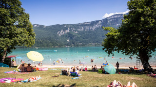 Personas se relajan junto al lago cerca de Saint Alban de Montbel, rodeados de montañas en Francia.