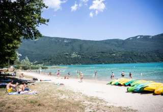 Gezinnen genieten aan het Huttopia Lac d’Aiguebelette met kajaks en bergen in Auvergne-Rhône-Alpes, Frankrijk.