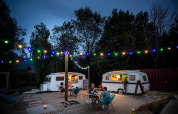 Aftenstemning ved Huttopia Lac d’Aiguebelette med madvogne, lyskæder og gæster på udendørs terrasse.