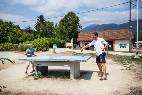 Vater und Sohn spielen Tischtennis im Freien auf einem Ferienpark in Auvergne-Rhône-Alpes, Frankreich.