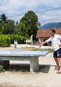 Padre e hijo juegan al ping-pong al aire libre en un parque vacacional en Auvergne-Rhône-Alpes, Francia.