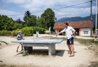 Padre e hijo juegan al ping-pong al aire libre en un parque vacacional en Auvergne-Rhône-Alpes, Francia.