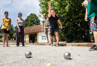 Folk spiller petanque på grus ved Huttopia Lac d’Aiguebelette, en feriepark i Auvergne-Rhône-Alpes, Frankrig.