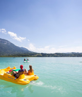Personas disfrutan del buen tiempo en barcas de pedales y paddle surf en el lago cerca de Saint Alban de Montbel.