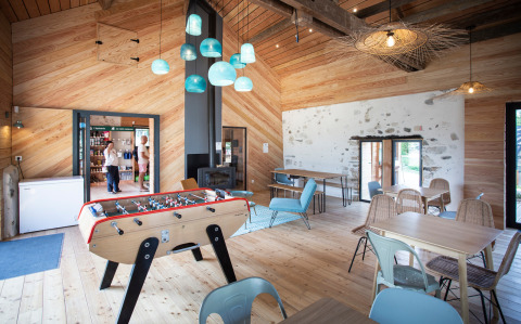 Sala común luminosa con futbolín y decoración moderna en Huttopia Lac d’Aiguebelette, Francia.