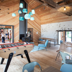 Sala común luminosa con futbolín y decoración moderna en Huttopia Lac d’Aiguebelette, Francia.