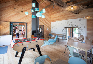 Lichte ontmoetingsruimte met tafelvoetbal en eigentijds interieur in Huttopia Lac d’Aiguebelette, Frankrijk.