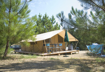 Safari-Zelt Toile&Bois tent Sweet bei Huttopia Oléron les Pins in Frankreich, umgeben von Kiefern.