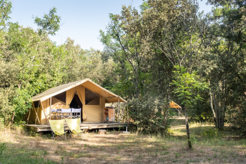 Safari-bungalowtelt Classic blandt træer ved Huttopia Oléron les Pins campingplads i Frankrig, sommerdag.
