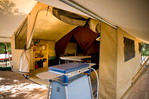 Inde i et Toile&bois Classic safaritelt på Huttopia Oléron les Pins, Frankrig, med køkken og spiseområde.