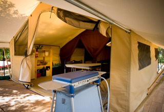 Interior de una tienda safari Toile&bois Classic en Huttopia Oléron les Pins, Francia, con cocina equipada.