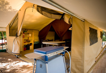 Interior of a Toile&bois Classic safari tent at Huttopia Oléron les Pins, France, featuring kitchen and dining.