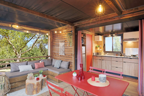 Interior de la tienda safari Arizona en Huttopia Oléron les Pins, Francia, con cocina y terraza acogedora.