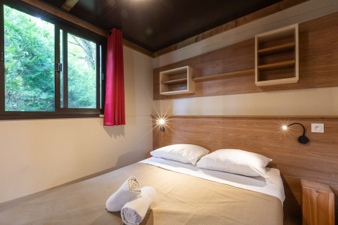 Interior del dormitorio de una tienda safari Arizona en Huttopia Oléron les Pins, Francia, con cama doble.