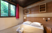 Interior del dormitorio de una tienda safari Arizona en Huttopia Oléron les Pins, Francia, con cama doble.