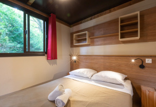 Slaapkamer met een tweepersoonsbed in een Arizona safaritent bij Huttopia Oléron les Pins in Frankrijk.