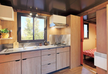 Vista moderna de cocina y dormitorio en una tienda safari Arizona en Huttopia Oléron les Pins, Francia.